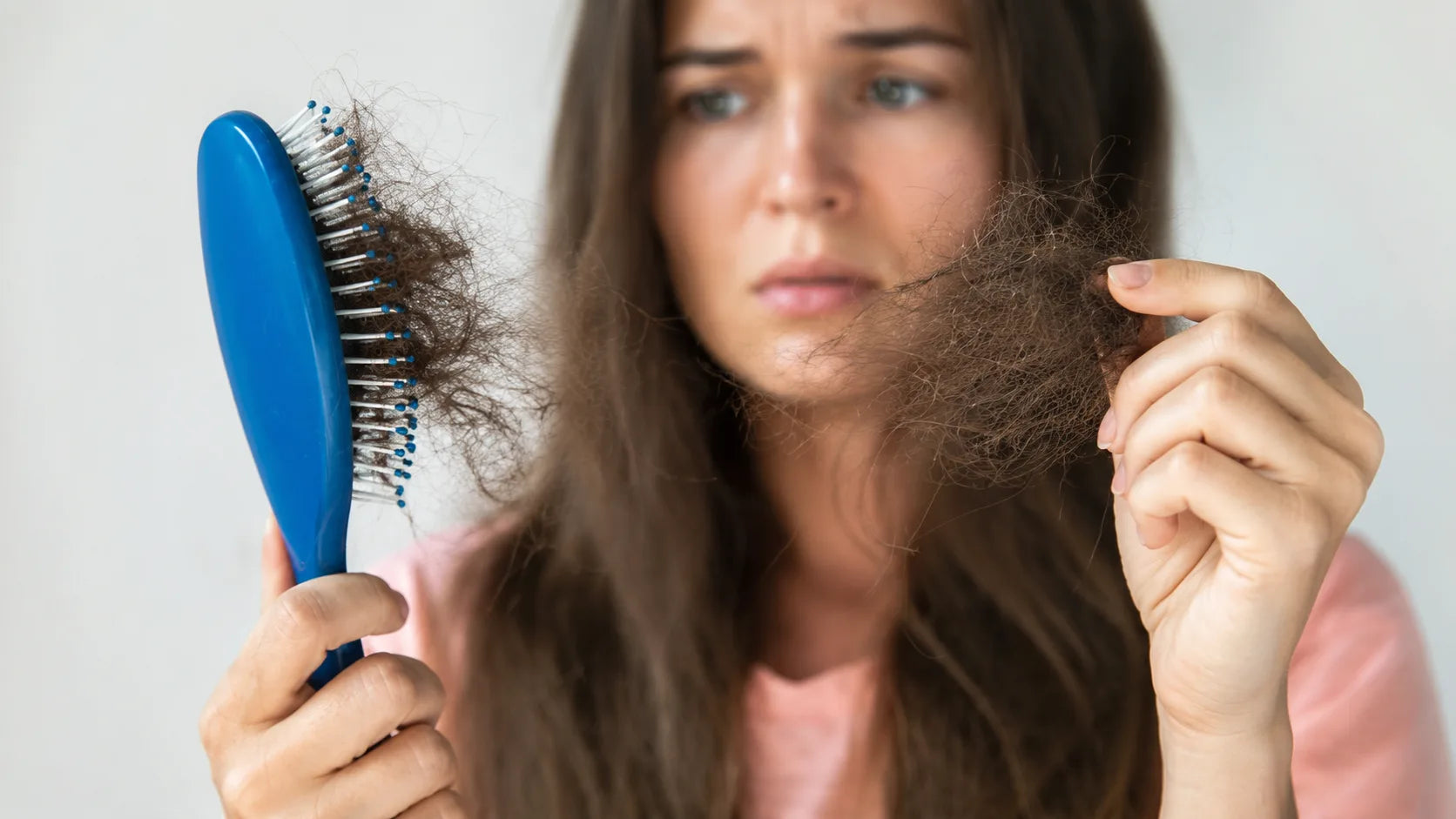 Jeune mère regardant une poignée de cheveux dans sa main après la douche